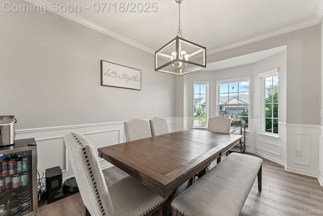 4074 Peach Tree Ln, Howell, MI 48843 - dining space featuring a chandelier, crown molding, a wainscoted wall, light wood-type flooring, and a decorative wall