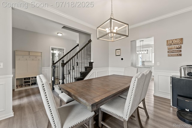 4074 Peach Tree Ln, Howell, MI 48843 - dining space featuring a chandelier, crown molding, wainscoting, wood finished floors, and a decorative wall