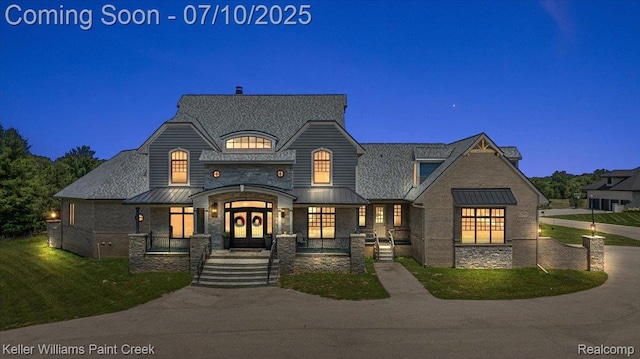 6295 Canter Creek Trl, Grand Blanc, MI 48439 - french country inspired facade featuring stone siding, a front lawn, french doors, and a standing seam roof