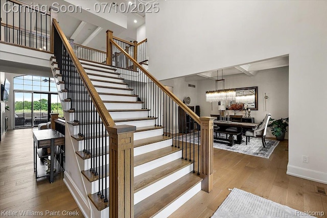 6295 Canter Creek Trl, Grand Blanc, MI 48439 - stairs featuring wood finished floors, a towering ceiling, beam ceiling, and a chandelier