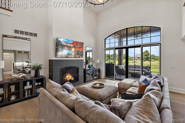 6295 Canter Creek Trl, Grand Blanc, MI 48439 - living room featuring a towering ceiling, light wood-style floors, and a tiled fireplace