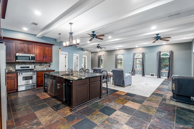 2624 Lynch, Highland, MI 48357 - kitchen with appliances with stainless steel finishes, ceiling fan, open floor plan, a wood stove, and tasteful backsplash