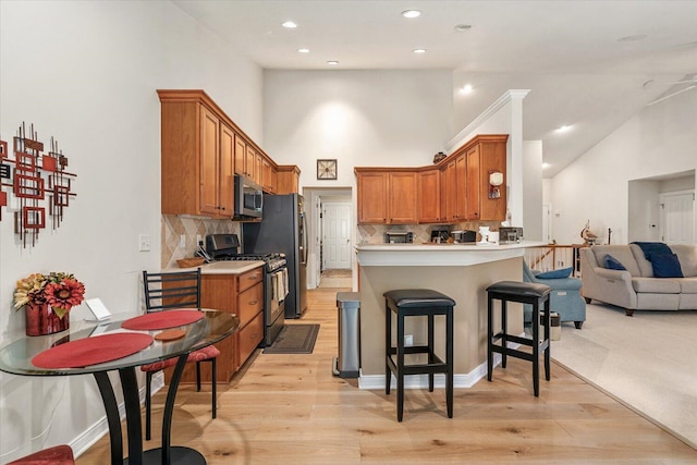 7520 Haflinger Cir, Kalamazoo, MI 49009 - kitchen featuring stainless steel appliances, brown cabinetry, open floor plan, backsplash, and a towering ceiling