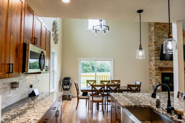2634 Fitzgerald Ave, Fremont, MI 49412 - kitchen with stainless steel microwave, backsplash, light wood-style floors, light stone counters, and a towering ceiling