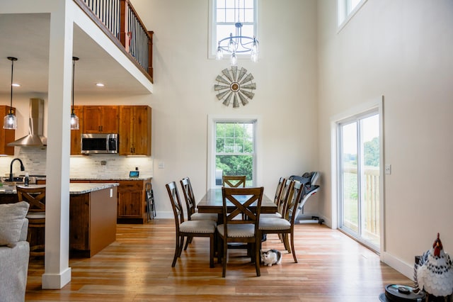 2634 Fitzgerald Ave, Fremont, MI 49412 - dining space featuring light wood-style flooring, a towering ceiling, and a chandelier