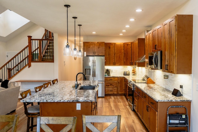 2634 Fitzgerald Ave, Fremont, MI 49412 - kitchen with appliances with stainless steel finishes, light wood-style flooring, a kitchen bar, recessed lighting, and under cabinet range hood