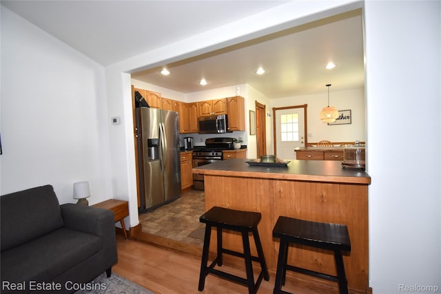 116 Park St, Gaines, MI 48436 - kitchen with appliances with stainless steel finishes, a peninsula, a breakfast bar area, wood finished floors, and dark countertops