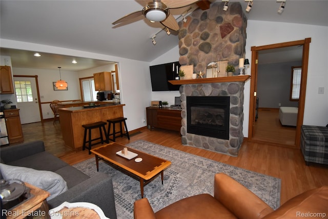 116 Park St, Gaines, MI 48436 - living area with lofted ceiling, ceiling fan, wood finished floors, a stone fireplace, and track lighting