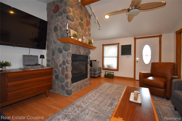 116 Park St, Gaines, MI 48436 - living room featuring lofted ceiling, wood finished floors, a ceiling fan, and a stone fireplace