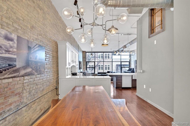 127 S Union St, Traverse City, MI 49684 - dining area with dark wood finished floors, a chandelier, and brick wall