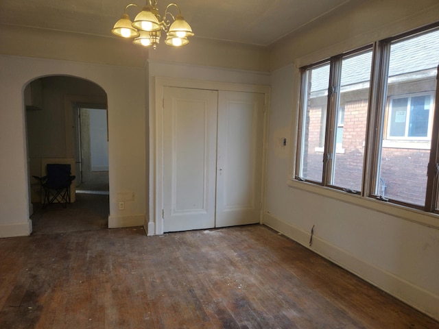 3742 W Grand St, Detroit, MI 48238 - unfurnished bedroom featuring arched walkways, wood-type flooring, a chandelier, a closet, and multiple windows