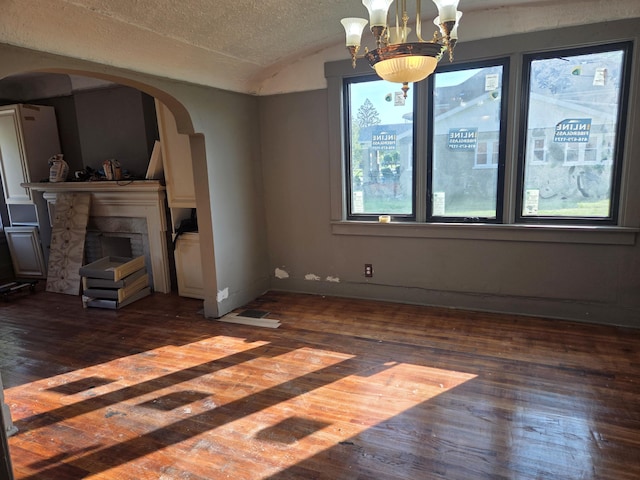 3742 W Grand St, Detroit, MI 48238 - unfurnished living room with arched walkways, dark wood-type flooring, vaulted ceiling, a fireplace, and a chandelier