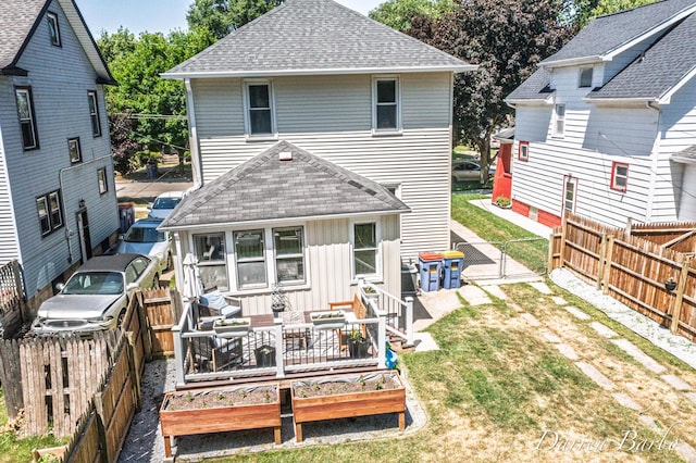 1118 Sibley St NW, Grand Rapids, MI 49504 - back of house featuring roof with shingles, a garden, board and batten siding, a gate, and a fenced backyard