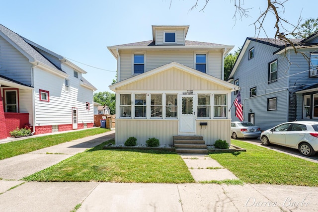 1118 Sibley St NW, Grand Rapids, MI 49504 - traditional style home with board and batten siding, entry steps, a front yard, and a sunroom