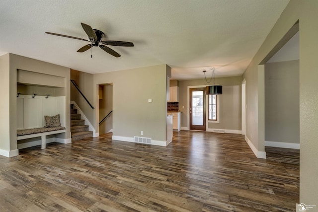 7558 Indian Rd, Temperance, MI 48182 - unfurnished living room with dark wood finished floors, stairs, ceiling fan, and a textured ceiling