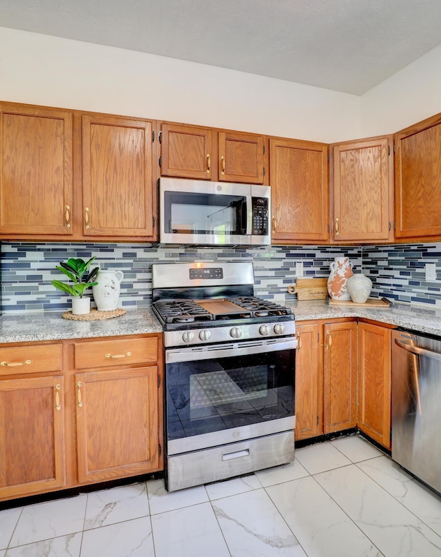 10895 Riley St, Zeeland, MI 49464 - kitchen with stainless steel appliances, light marble finish floors, brown cabinetry, and decorative backsplash