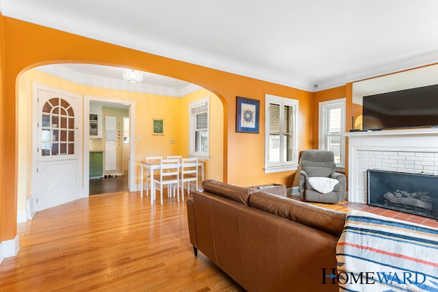 660 Deming St SE, Grand Rapids, MI 49507 - living area featuring arched walkways, light wood-style flooring, a brick fireplace, and ornamental molding