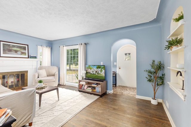 2013 Duiker Ave NE, Grand Rapids, MI 49505 - living room with arched walkways, wood finished floors, a textured ceiling, and a glass covered fireplace