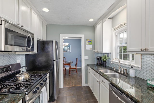 2013 Duiker Ave NE, Grand Rapids, MI 49505 - kitchen with appliances with stainless steel finishes, a textured ceiling, white cabinets, dark stone countertops, and decorative backsplash