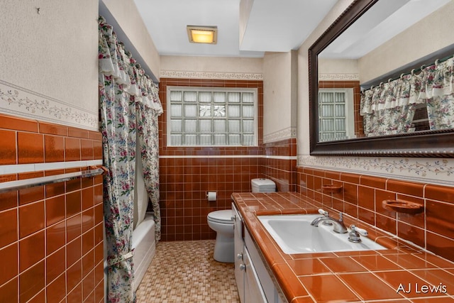 2155 Lake Michigan Dr NW, Grand Rapids, MI 49504 - full bathroom with tile walls, vanity, shower / bathtub combination with curtain, and a wainscoted wall