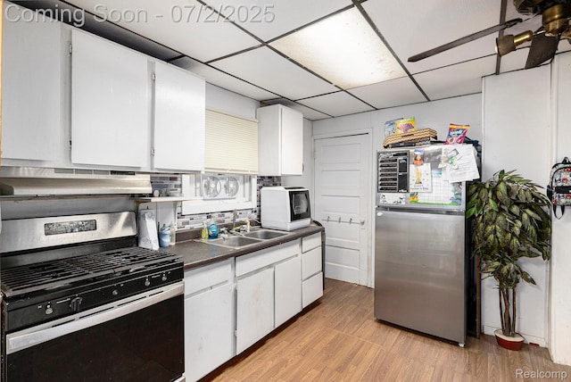 1323 Rhodes St, Jackson, MI 49202 - kitchen featuring stainless steel appliances, dark countertops, a drop ceiling, under cabinet range hood, and light wood finished floors