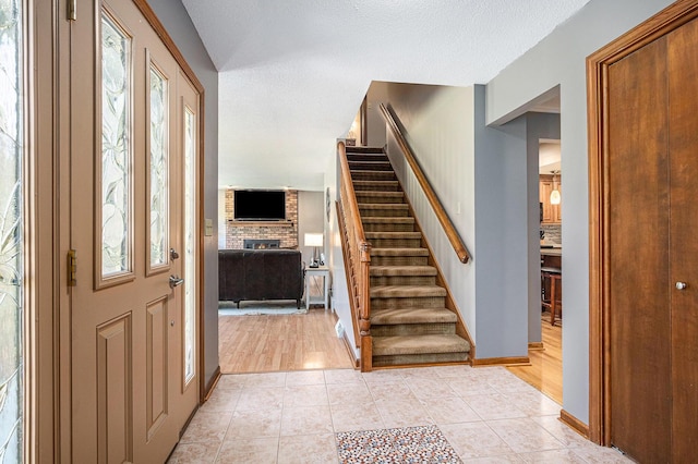 4102 Tomahawk Way, Saint Joseph, MI 49085 - entryway with a fireplace, stairway, light tile patterned floors, and a textured ceiling