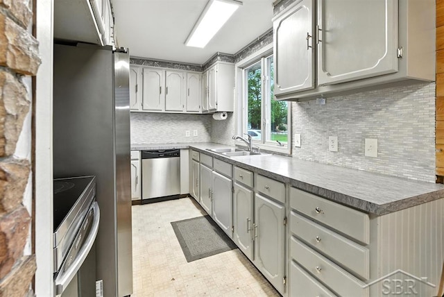 534 S Main St, Au Gres, MI 48703 - kitchen with appliances with stainless steel finishes, light floors, gray cabinets, and decorative backsplash