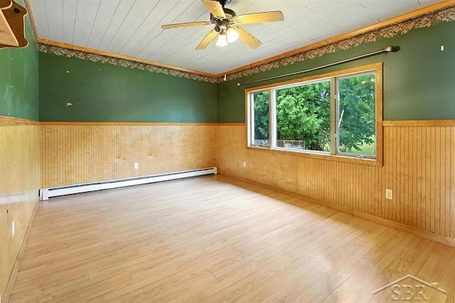 534 S Main St, Au Gres, MI 48703 - spare room featuring baseboard heating, a wainscoted wall, wood finished floors, wood walls, and ceiling fan