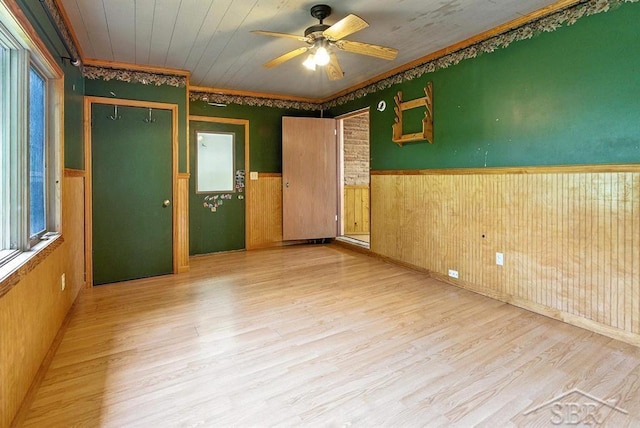 534 S Main St, Au Gres, MI 48703 - spare room featuring a wainscoted wall, light wood-style flooring, a ceiling fan, wood walls, and crown molding