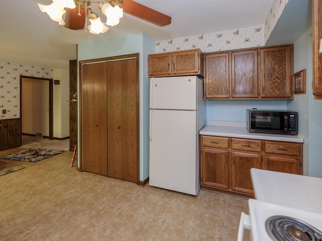 461 19th St, Otsego, MI 49078 - kitchen featuring freestanding refrigerator, stainless steel microwave, wallpapered walls, light countertops, and brown cabinetry