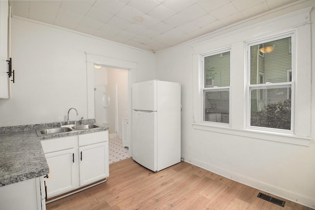 811 Larned St, Lansing, MI 48912 - kitchen with freestanding refrigerator, white cabinets, and light wood-style floors