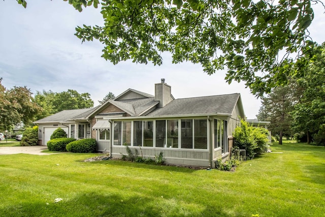 5546 Hickory Cir, Flushing, MI 48433 - rear view of property featuring a sunroom, a chimney, a garage, a yard, and roof with shingles