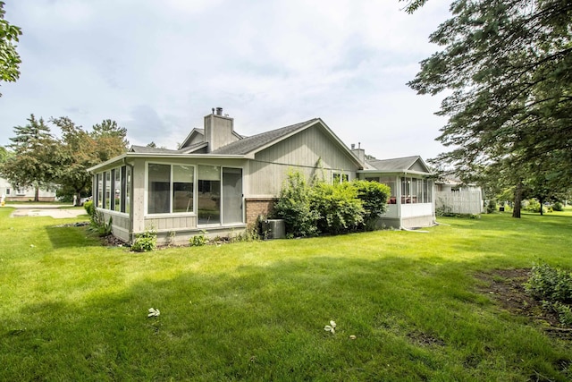5546 Hickory Cir, Flushing, MI 48433 - rear view of property featuring a sunroom, a chimney, and a yard