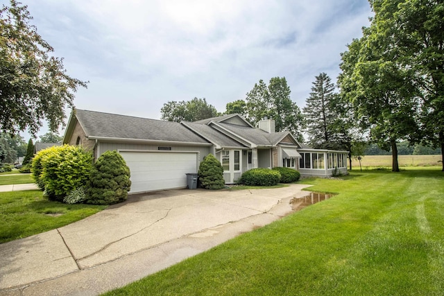 5546 Hickory Cir, Flushing, MI 48433 - view of front of house with a chimney, an attached garage, a front yard, driveway, and a sunroom