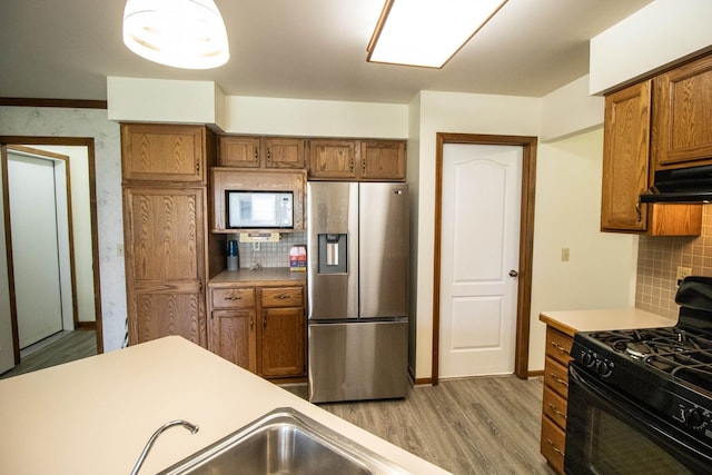 5546 Hickory Cir, Flushing, MI 48433 - kitchen featuring stainless steel refrigerator with ice dispenser, black range with gas stovetop, white microwave, wood finished floors, and brown cabinetry