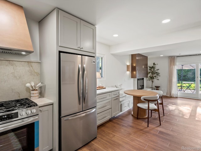3025 Clawson Ave, Royal Oak, MI 48073 - kitchen featuring appliances with stainless steel finishes, premium range hood, light wood finished floors, backsplash, and recessed lighting