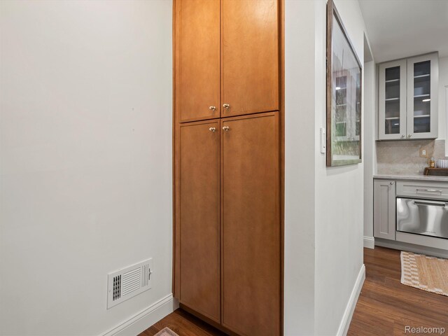 3025 Clawson Ave, Royal Oak, MI 48073 - kitchen featuring dark wood finished floors, glass insert cabinets, light countertops, and backsplash