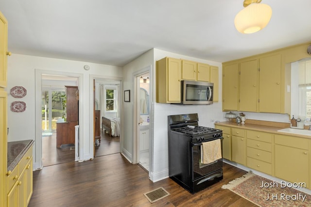 1802 Cherry St, Dorr, MI 49323 - kitchen with black gas range oven, stainless steel microwave, dark wood-style flooring, tasteful backsplash, and cream cabinetry