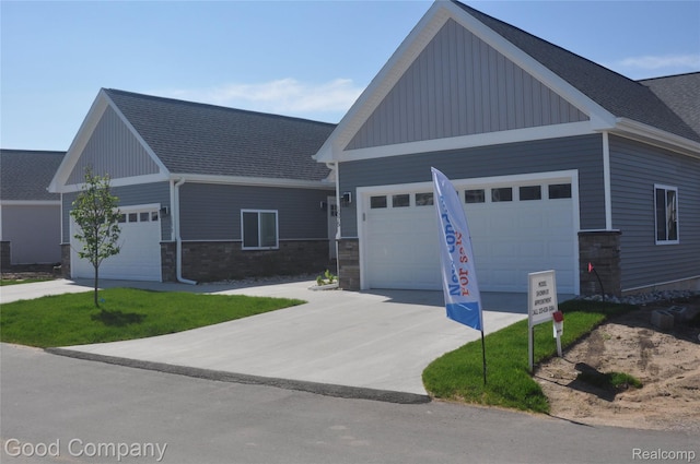 1530 Parmenter Ct Unit 18, Petoskey, MI 49770 - view of front of property with board and batten siding, an attached garage, driveway, a shingled roof, and stone siding