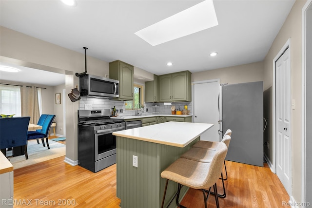 30695 Lyndon St, Livonia, MI 48154 - kitchen with green cabinets, appliances with stainless steel finishes, light countertops, decorative backsplash, and light wood-style floors