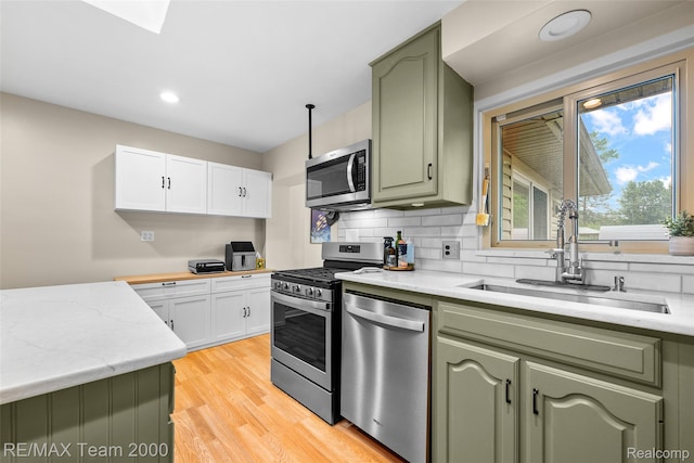 30695 Lyndon St, Livonia, MI 48154 - kitchen featuring stainless steel appliances, green cabinets, light wood finished floors, recessed lighting, and decorative backsplash