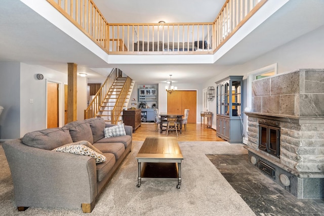 9719 King Rd, Spring Arbor, MI 49283 - living area with stairs, a high ceiling, a chandelier, a stone fireplace, and wood finished floors
