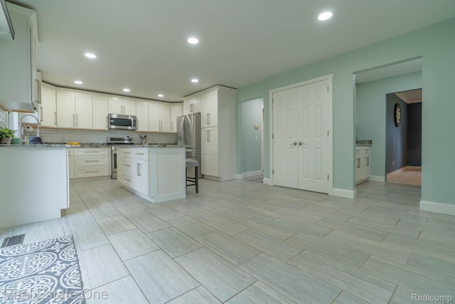 14607 Stratford, Shelby Twp, MI 48315 - kitchen with appliances with stainless steel finishes, white cabinetry, recessed lighting, a kitchen bar, and a kitchen island