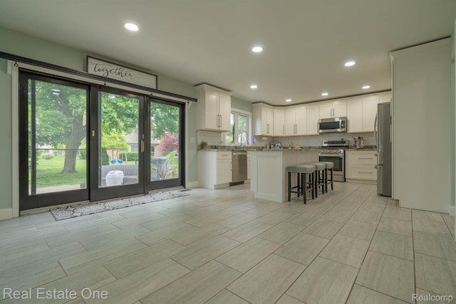 14607 Stratford, Shelby Twp, MI 48315 - kitchen featuring stainless steel appliances, decorative backsplash, white cabinetry, a breakfast bar area, and a center island