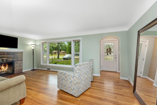 437 Collindale Ave NW, Grand Rapids, MI 49504 - living room featuring a stone fireplace, light wood finished floors, and arched walkways
