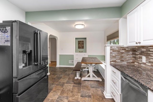 437 Collindale Ave NW, Grand Rapids, MI 49504 - kitchen featuring appliances with stainless steel finishes, arched walkways, white cabinetry, backsplash, and dark stone countertops