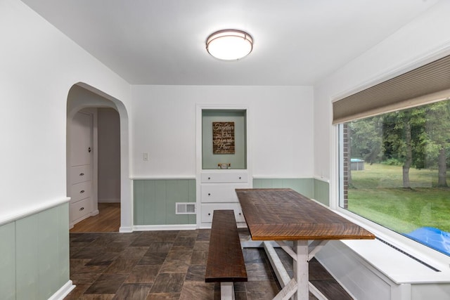 437 Collindale Ave NW, Grand Rapids, MI 49504 - dining area featuring wainscoting, arched walkways, and dark stone finish floors