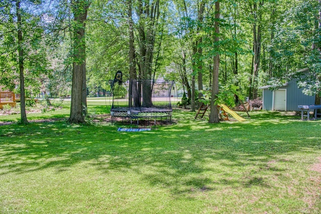 279 Ardelean Dr, Owosso, MI 48867 - view of grassy yard featuring a trampoline, a playground, and an outbuilding