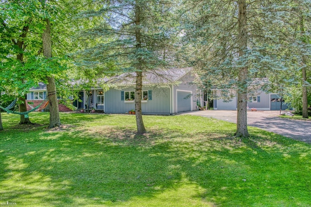 279 Ardelean Dr, Owosso, MI 48867 - view of front facade featuring concrete driveway, an attached garage, a front lawn, and board and batten siding