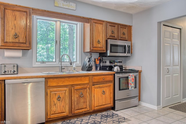 279 Ardelean Dr, Owosso, MI 48867 - kitchen with appliances with stainless steel finishes, brown cabinets, light tile patterned floors, and light countertops